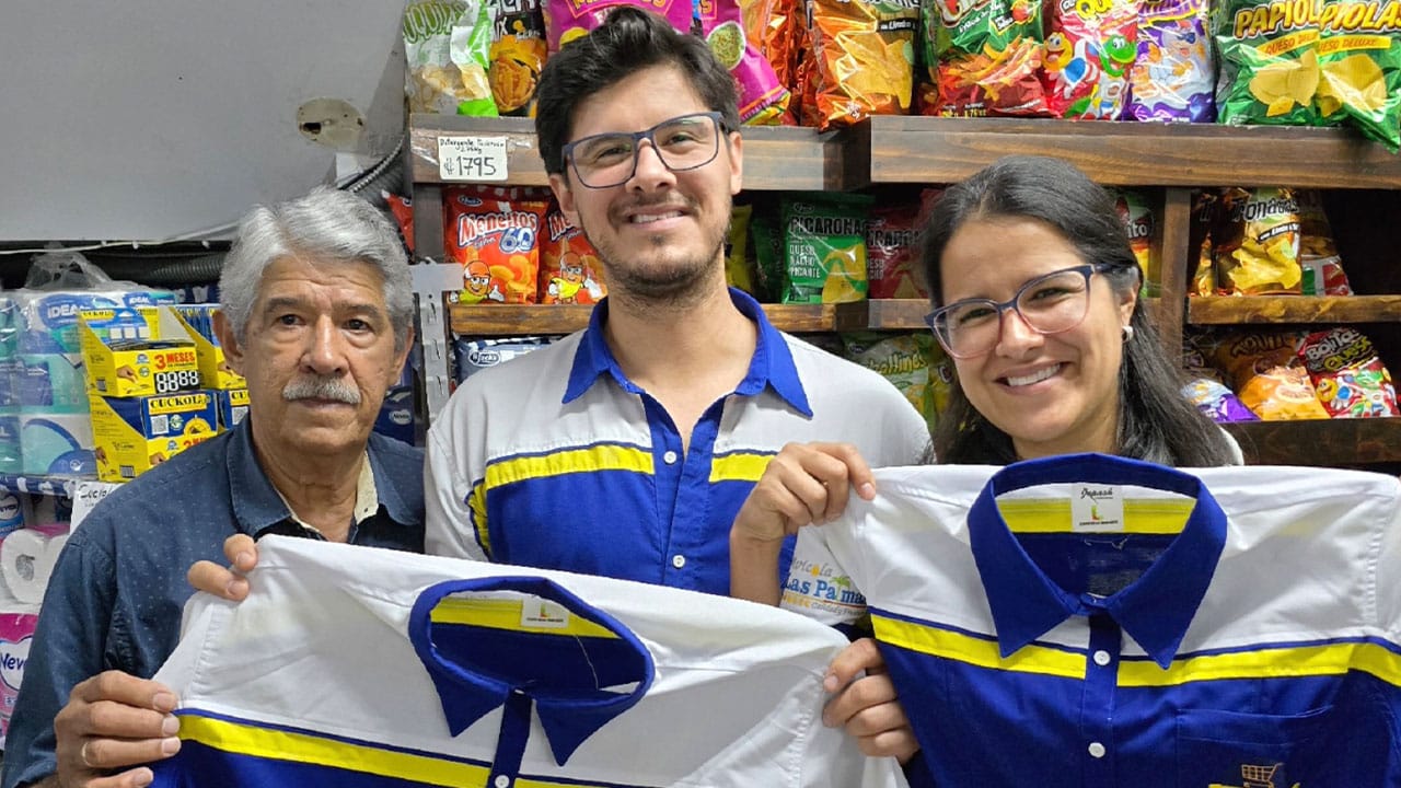 Carlos and his father with another team member holding shirts inside the store.